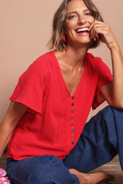 Model Riina wearing size 10 of the Cute As A Button Blouse in colour Red (Red), from the front, cropped image