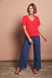 Model Riina wearing size 10 of the Cute As A Button Blouse in colour Red (Red), from the front, showing the whole outfit