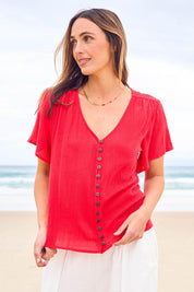Model Tegan wearing size 10 of the Cute As A Button Blouse in colour Red (Red), from the front, showing the whole outfit