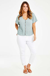 Model Laura wearing size 14 of the Cute As A Button Blouse in colour Sage (Green), from the front, showing the whole outfit