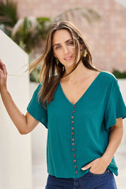 Model Tegand wearing size 10 of the Cute As A Button Blouse - Teal in colour Teal, in a cropped view