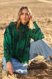 Model Cara wearing size 10 of the Romance In The Air Blouse in colour Emerald (Green), from the front, showing the whole outfit