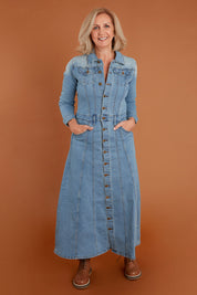 Model Sandy wearing size 10 of the Calamity Denim Maxi Dress in colour Denim (Blue), from the front, showing the whole outfit