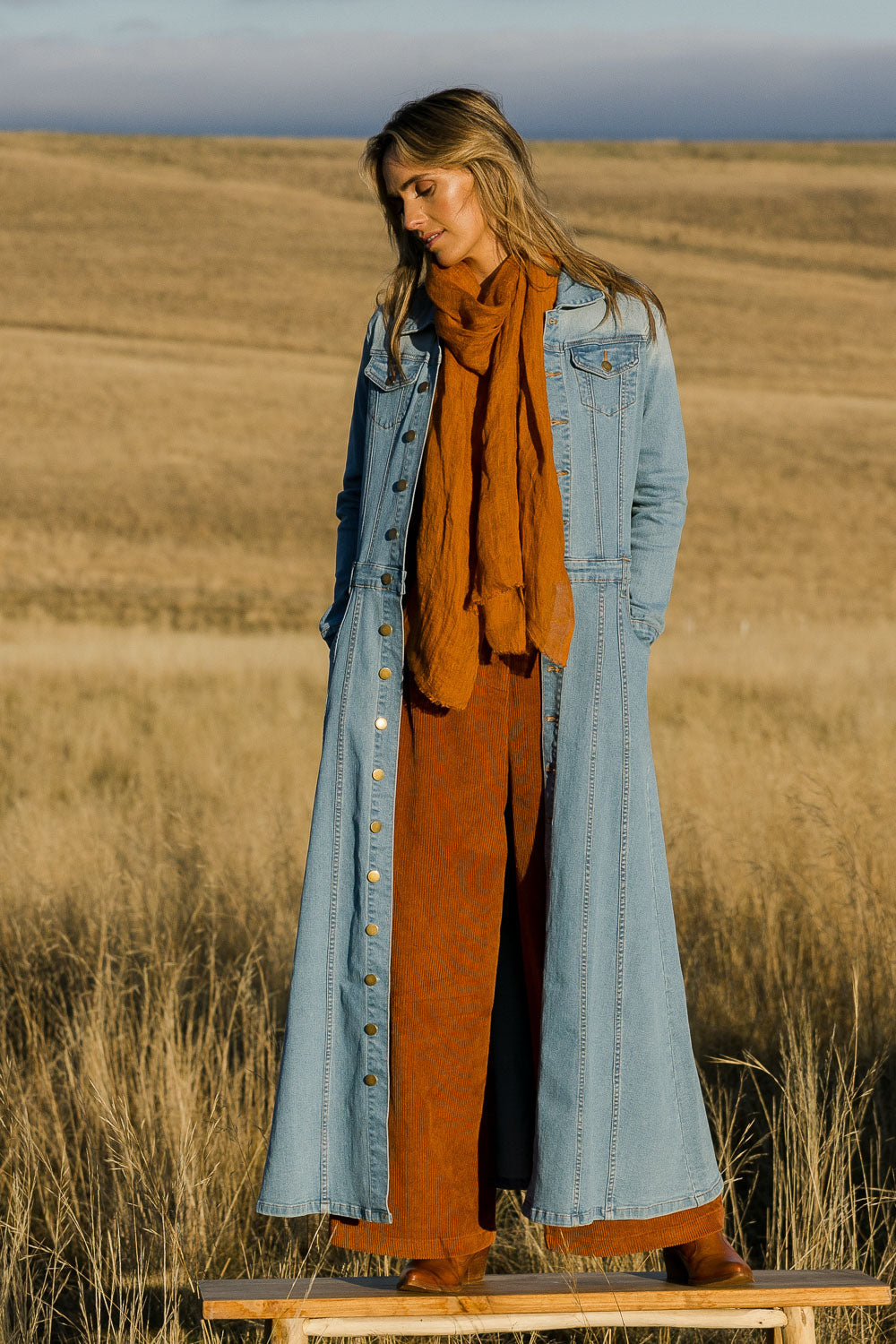 Model Tegan wearing size 10 of the Calamity Denim Maxi Dress in colour Denim (Blue), from the front, showing the whole outfit