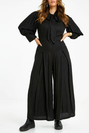 Model Laura wearing size 14 of the Feeling Super Fine Jumpsuit in colour Black (Black), from the front, cropped image