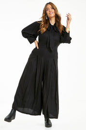 Model Laura wearing size 14 of the Feeling Super Fine Jumpsuit in colour Black (Black), from the front, showing the whole outfit