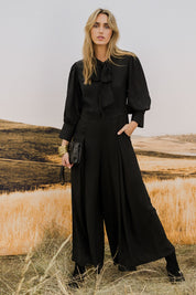 Model Tegan wearing size 10 of the Feeling Super Fine Jumpsuit in colour Black (Black), from the front, showing the whole outfit