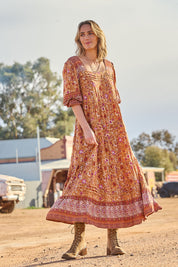 Model Tegan wearing size 10 of the Paradise Found Maxi Dress in colour Rustfleur, from the front, showing the whole outfit