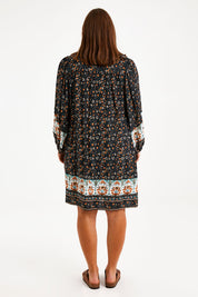 Model Monique wearing size 14 of the Sunset Dreamer Dress in colour Blkfleur (Black), from the back