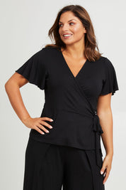 Model Monique wearing size 14 of the All For You Wrap Top in colour Black (Black), from the front, cropped image