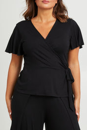 Model Monique wearing size 14 of the All For You Wrap Top in colour Black (Black), from the front, cropped image