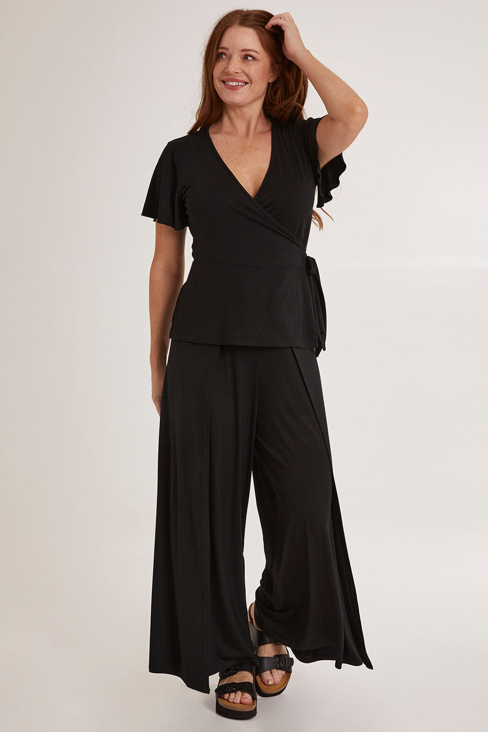 Model Sally wearing size 10 of the All For You Wrap Top in colour Black (Black), from the front, showing the whole outfit