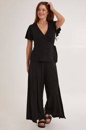Model Sally wearing size 10 of the All For You Wrap Top in colour Black (Black), from the front, showing the whole outfit