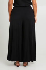 Model Monique wearing size 14 of the All For You Wrap Pants in colour Black (Black), from the back