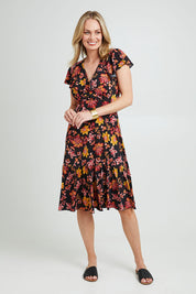 Model Grace wearing size 10 of The Frill You Give Me Dress in colour Blkfleur (Black), from the front, showing the whole outfit