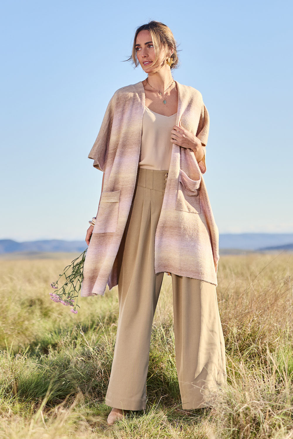 Model Tegan wearing the Mountain Fields Cardi in colour Sunset (Pink), from the front, showing the whole outfit