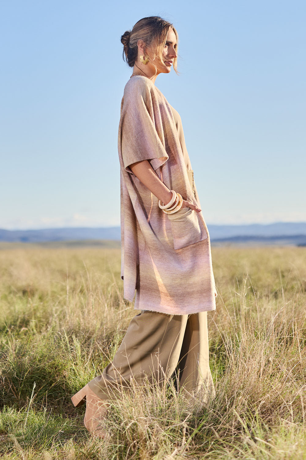 Model Tegan wearing the Mountain Fields Cardi in colour Sunset (Pink), from the front, showing the whole outfit