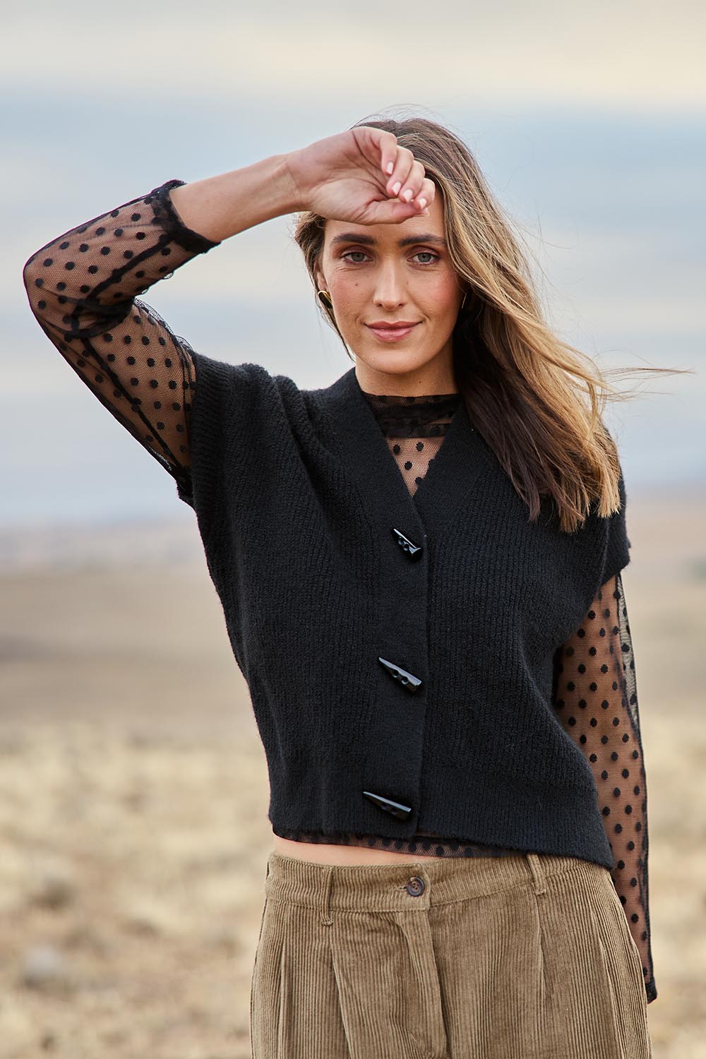 Model Tegan wearing size S of the Found My Friend Recycled Knit Sleeveless Cardi in colour Black (Black), from the front, showing the whole outfit