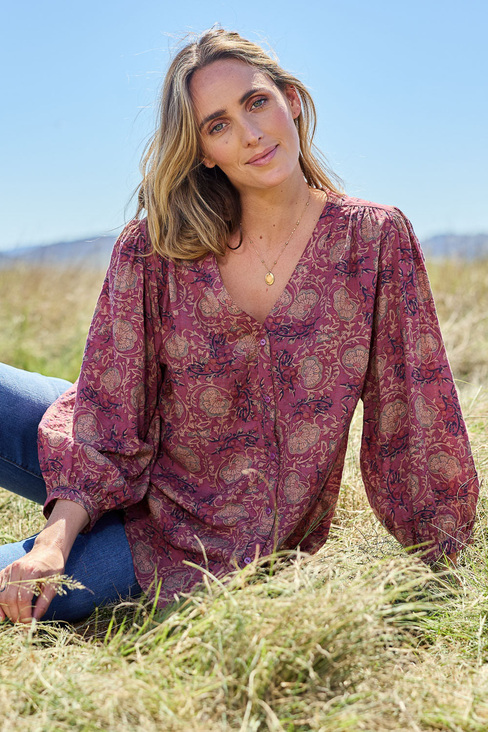 Model Tegan wearing size 10 of the Easy On Me Blouse in colour Plum (Purple), from the front, showing the whole outfit