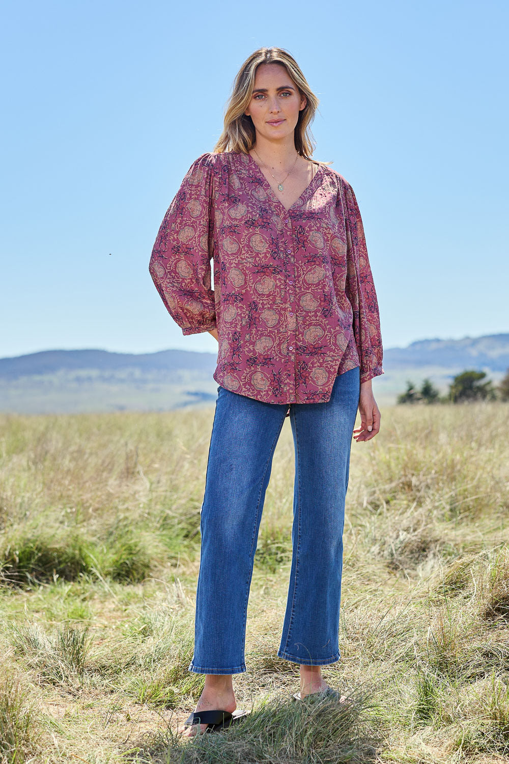 Model Tegan wearing size 10 of the Easy On Me Blouse in colour Plum (Purple), from the front, showing the whole outfit