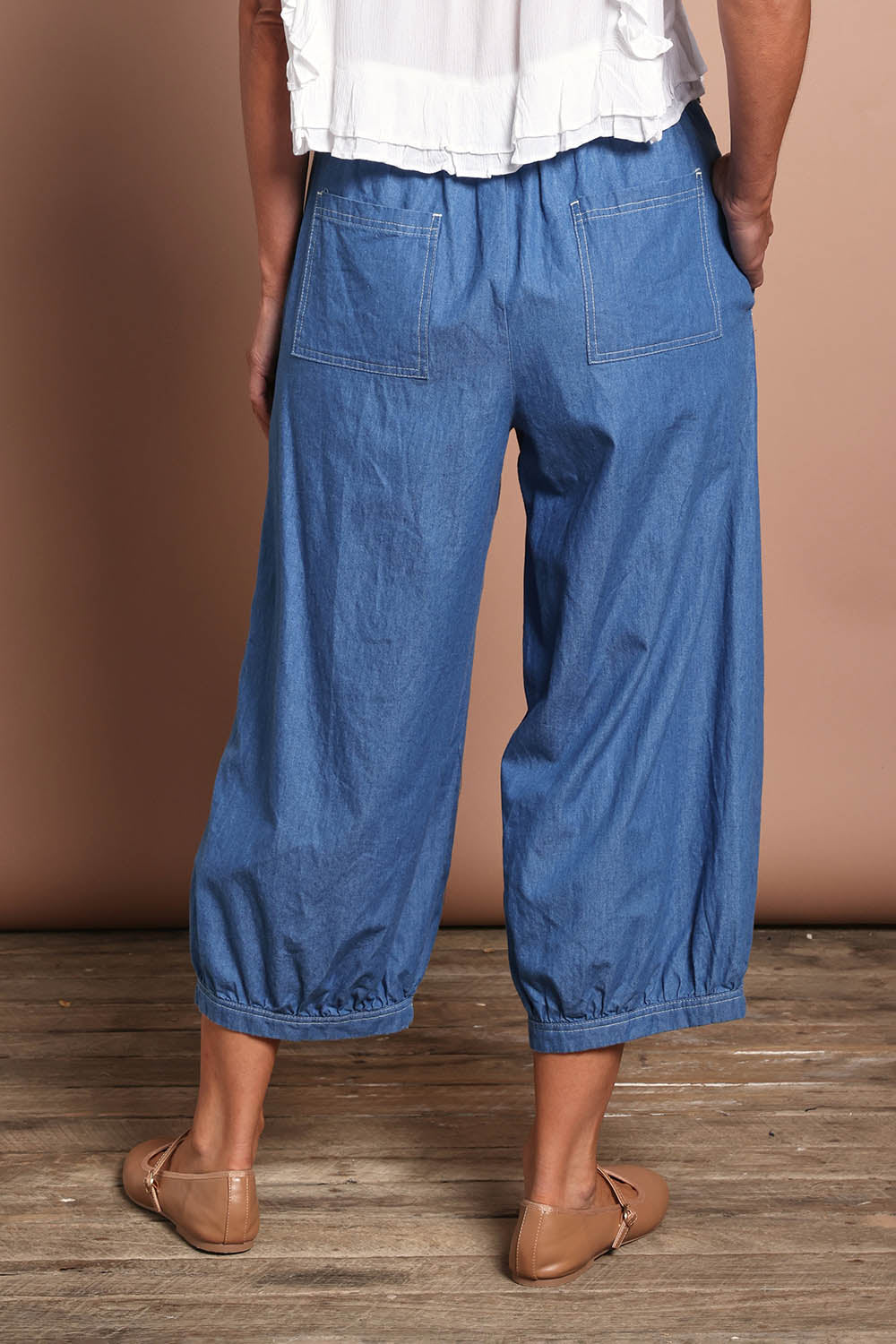 Model Riina wearing size 10 of the Summer Daze Denim Pull On 3/4 Pant in colour Denim (Blue), from the back