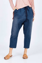 Model Georgia wearing size 10 of the Just Chillin Stretch Dropped Crotch Jeans in colour Denim (Blue), from the front, cropped image
