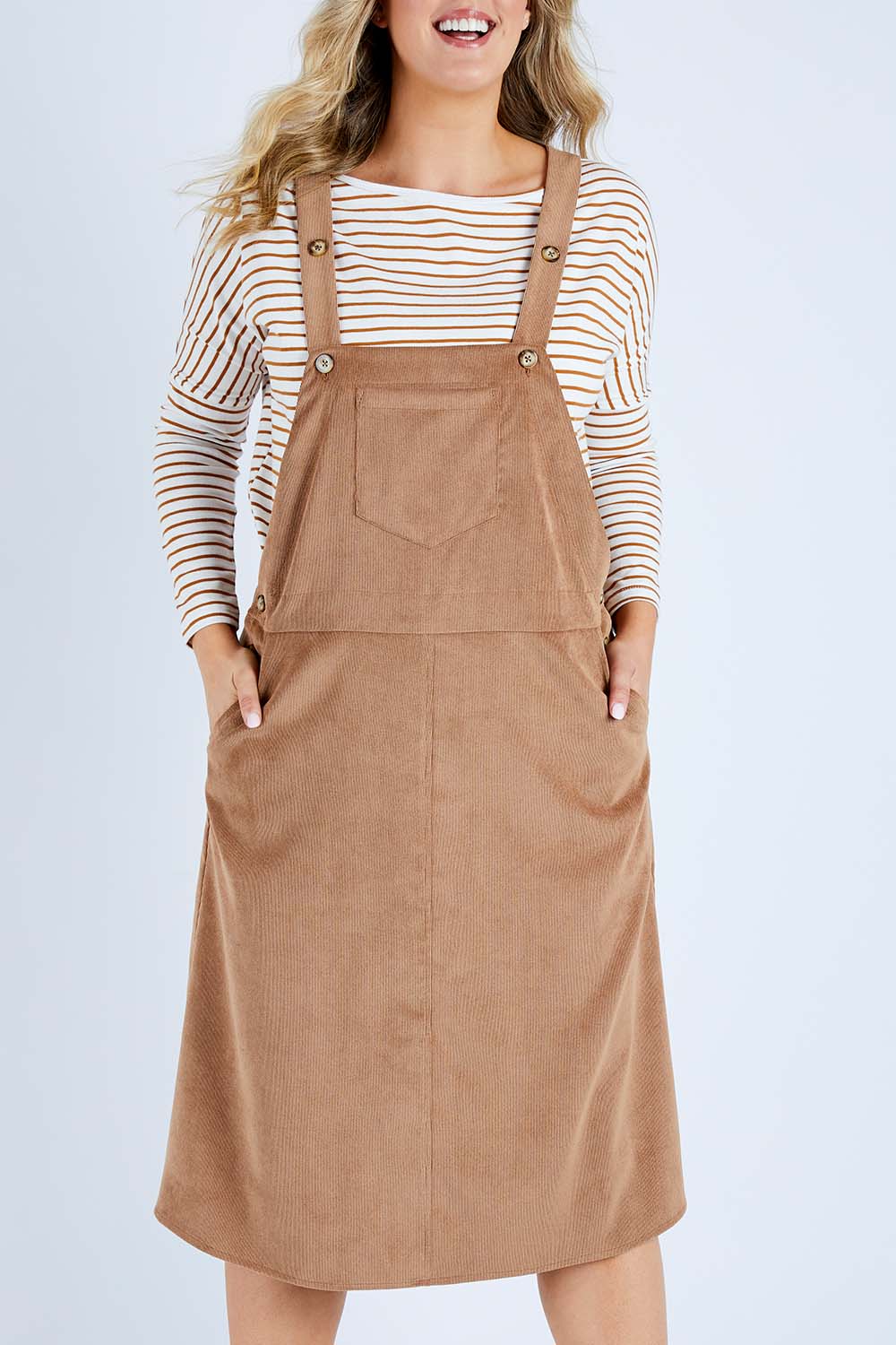 Model Jess wearing size 14 of the My Cord Pinafore Dress in colour Camel, from the front, cropped image