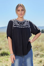 Model Tegan wearing size 10 of the Secret Garden Cotton Blouse in colour Black (Black), from the front, showing the whole outfit