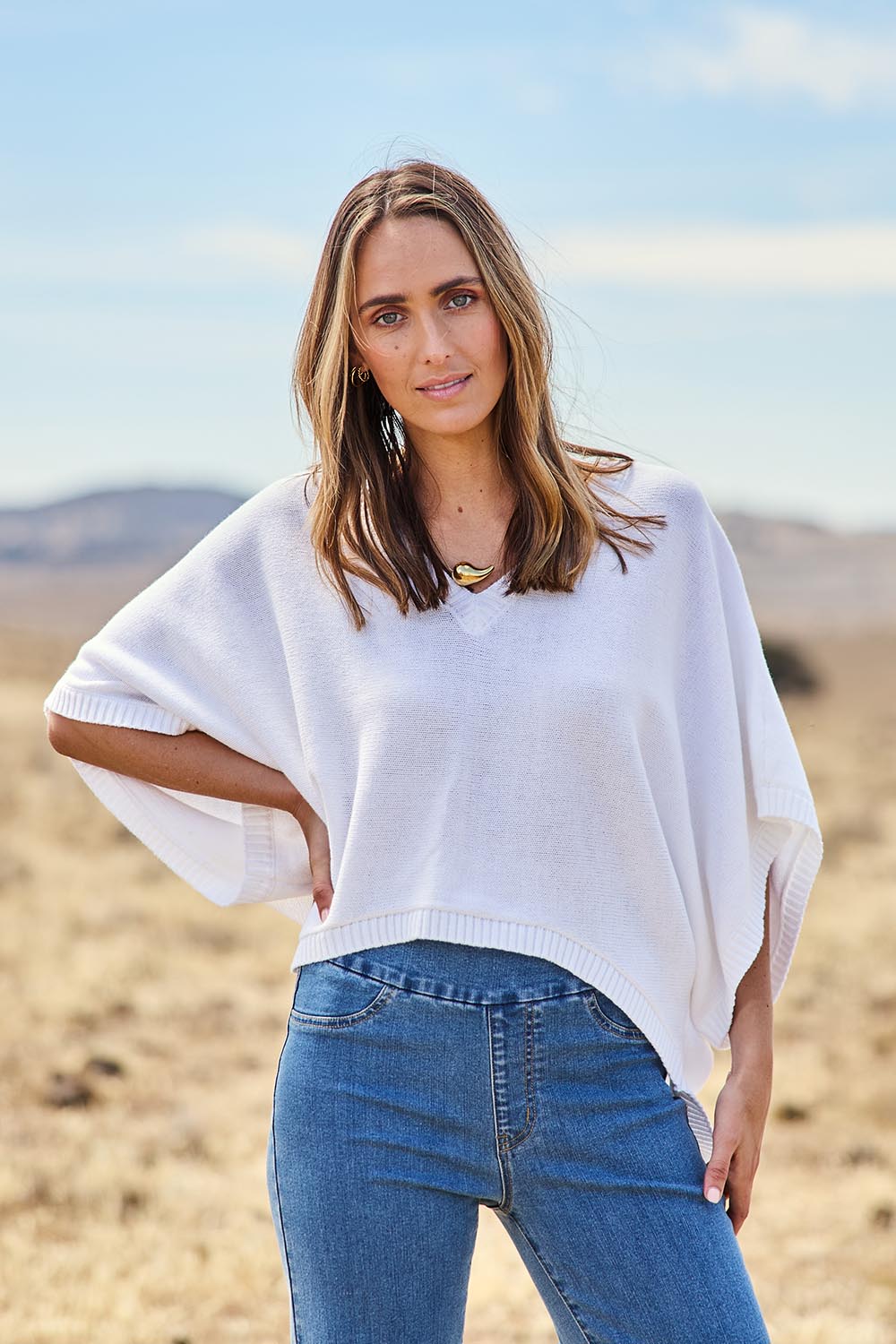Model Tegan wearing size S of the Knit Pick Throw V Neck Sweater in colour Milk (White), from the front, showing the whole outfit