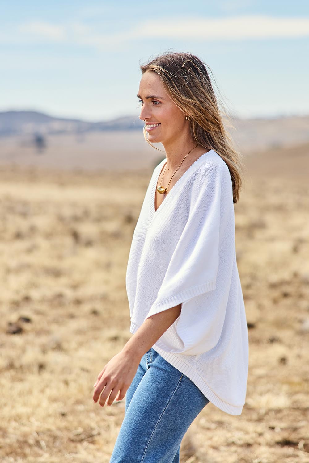 Model Tegan wearing size S of the Knit Pick Throw V Neck Sweater in colour Milk (White), from the front, showing the whole outfit
