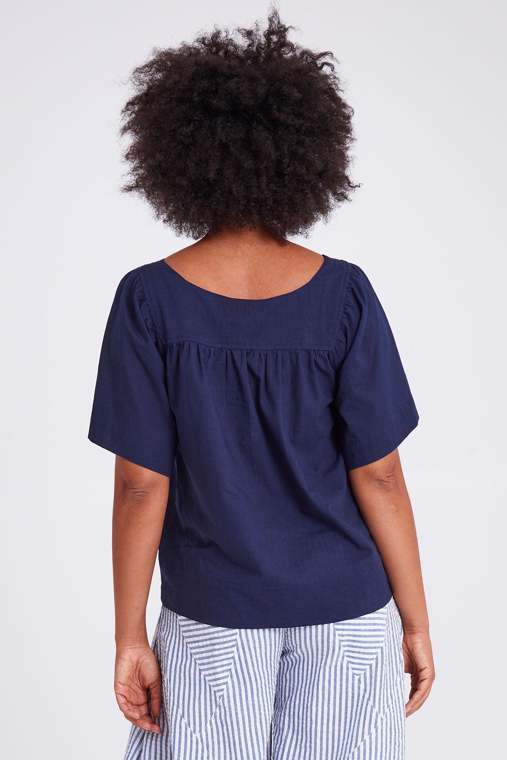 Model Olivia wearing size 10 of the Freya Top in colour Navy (Blue), from the back