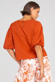 A model wearing the Ava Cotton Top in colour Mecca, from the back