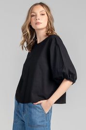 A model wearing the Ava Top in colour Black (Black), from the front, cropped image