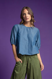 A model wearing the Ava Top in colour Chambray (Blue), from the front, showing the whole outfit