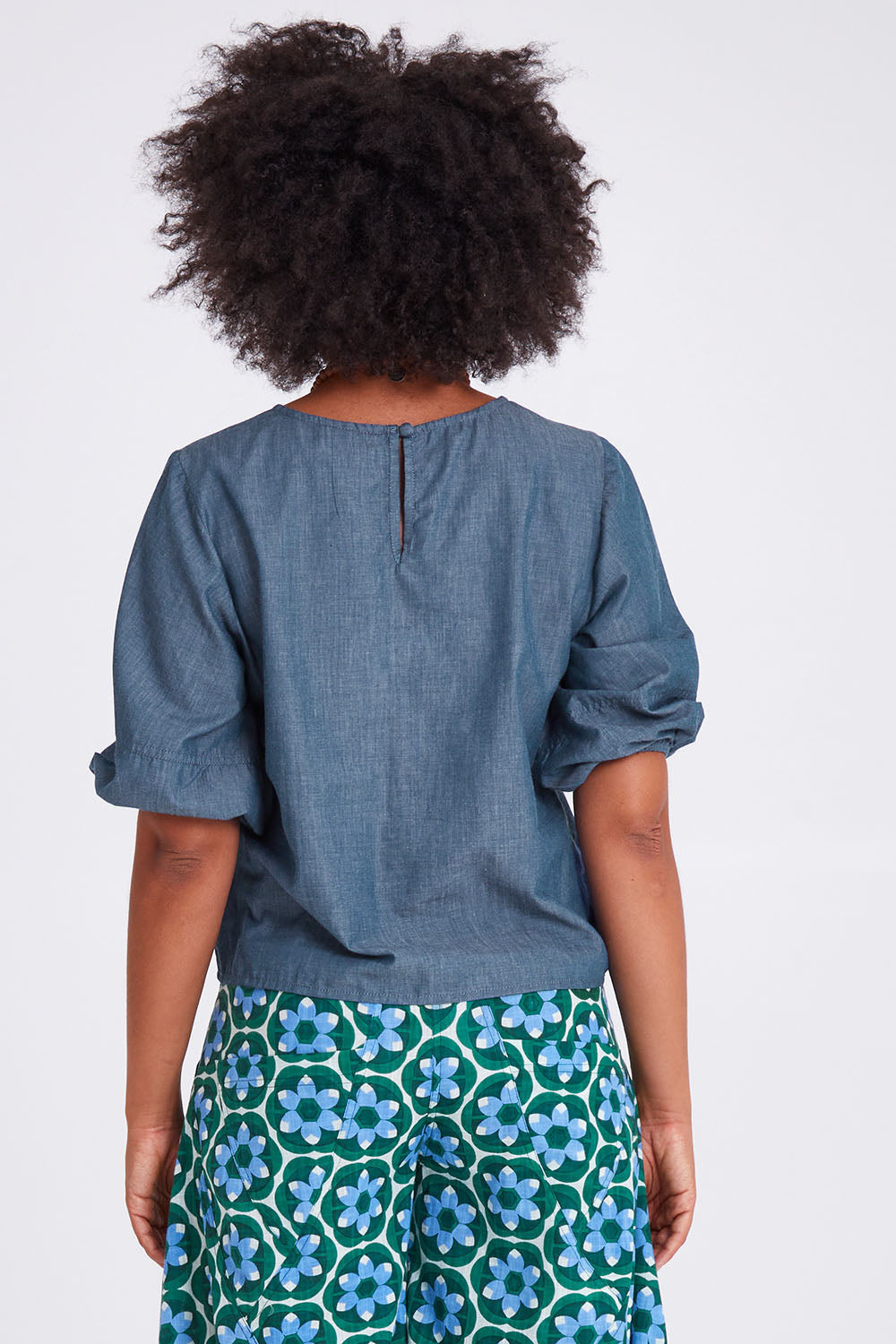 Model Olivia wearing size 10 of the Ava Top in colour Chambray (Blue), from the back