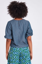 Model Olivia wearing size 10 of the Ava Top in colour Chambray (Blue), from the back