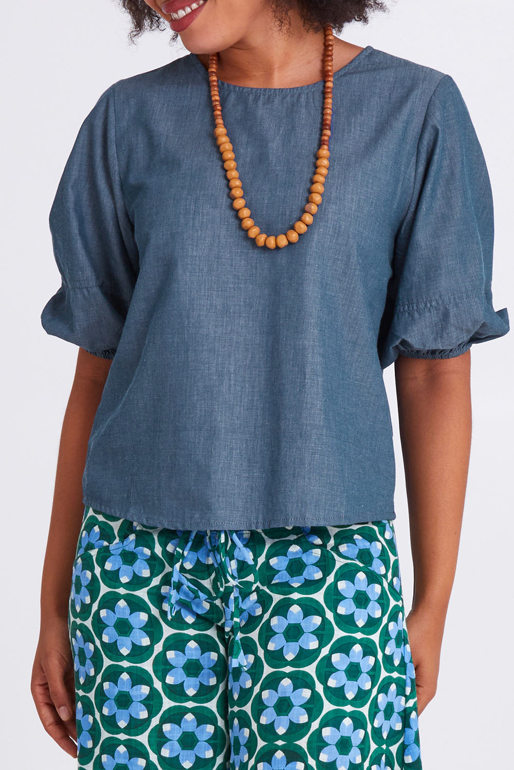 Model Olivia wearing size 10 of the Ava Top in colour Chambray (Blue), from the front, cropped image