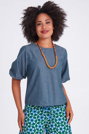 Model Olivia wearing size 10 of the Ava Top in colour Chambray (Blue), from the front, cropped image