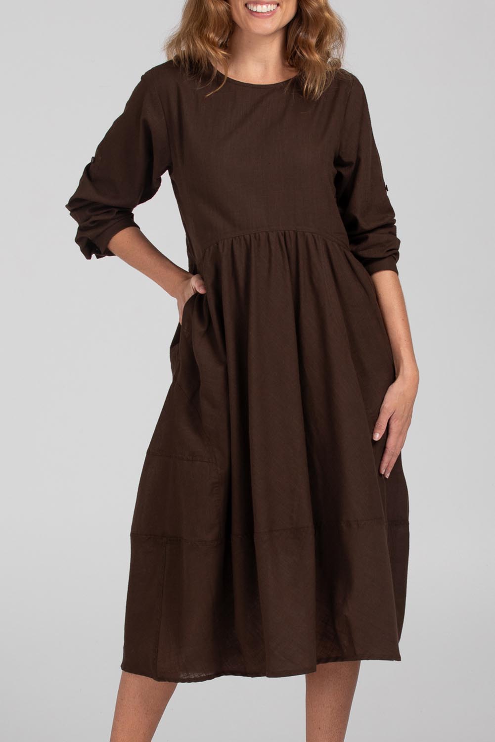 A model wearing the Guru Cotton Dress in colour Coffee, from the front, cropped image