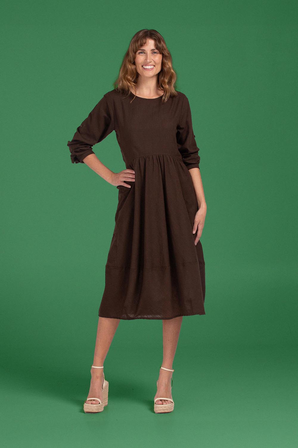 A model wearing the Guru Cotton Dress in colour Coffee, from the front, showing the whole outfit