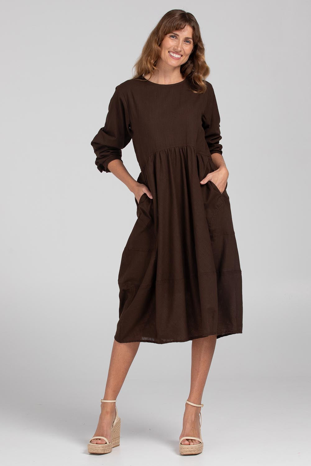 A model wearing the Guru Cotton Dress in colour Coffee, from the front, showing the whole outfit