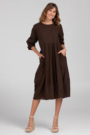 A model wearing the Guru Cotton Dress in colour Coffee, from the front, showing the whole outfit