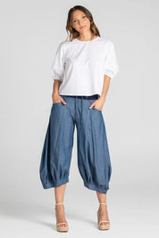 A model wearing the Guru Pant in colour Chambray (Blue), from the front, showing the whole outfit