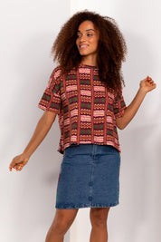 A model wearing the Holi Tee in colour Holi (Pink), from the front, showing the whole outfit