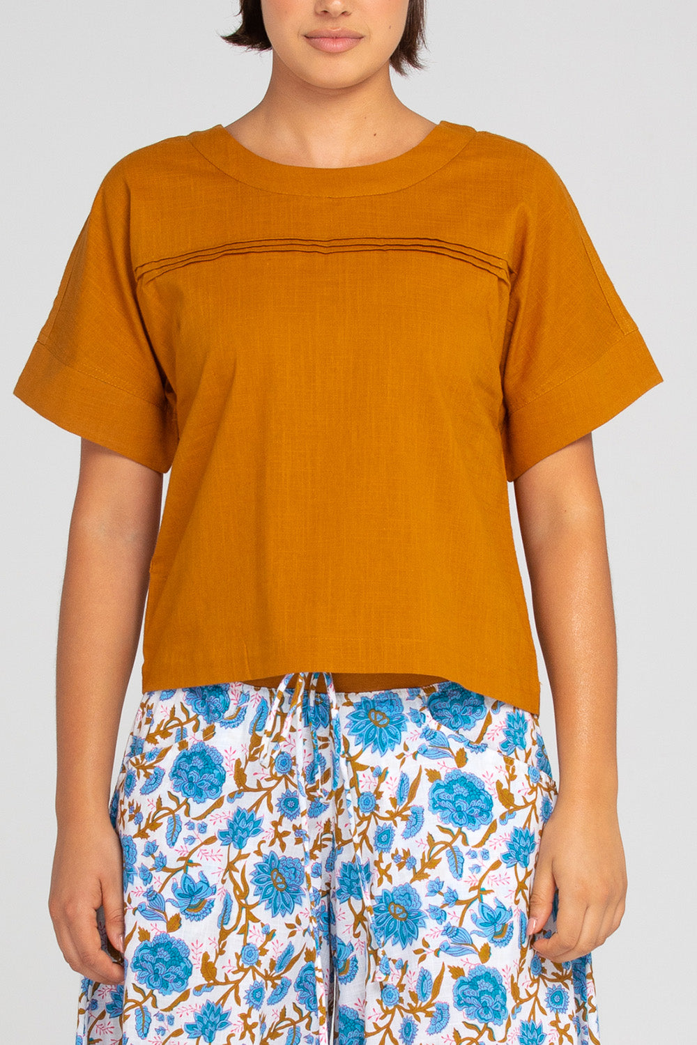 A model wearing the Haven Cotton Top in colour Mustard, from the front, cropped image