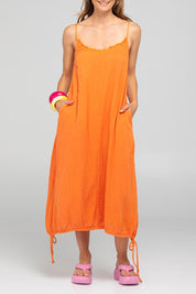 A model wearing the Arena Cotton Dress in colour Tangerine, from the front, cropped image