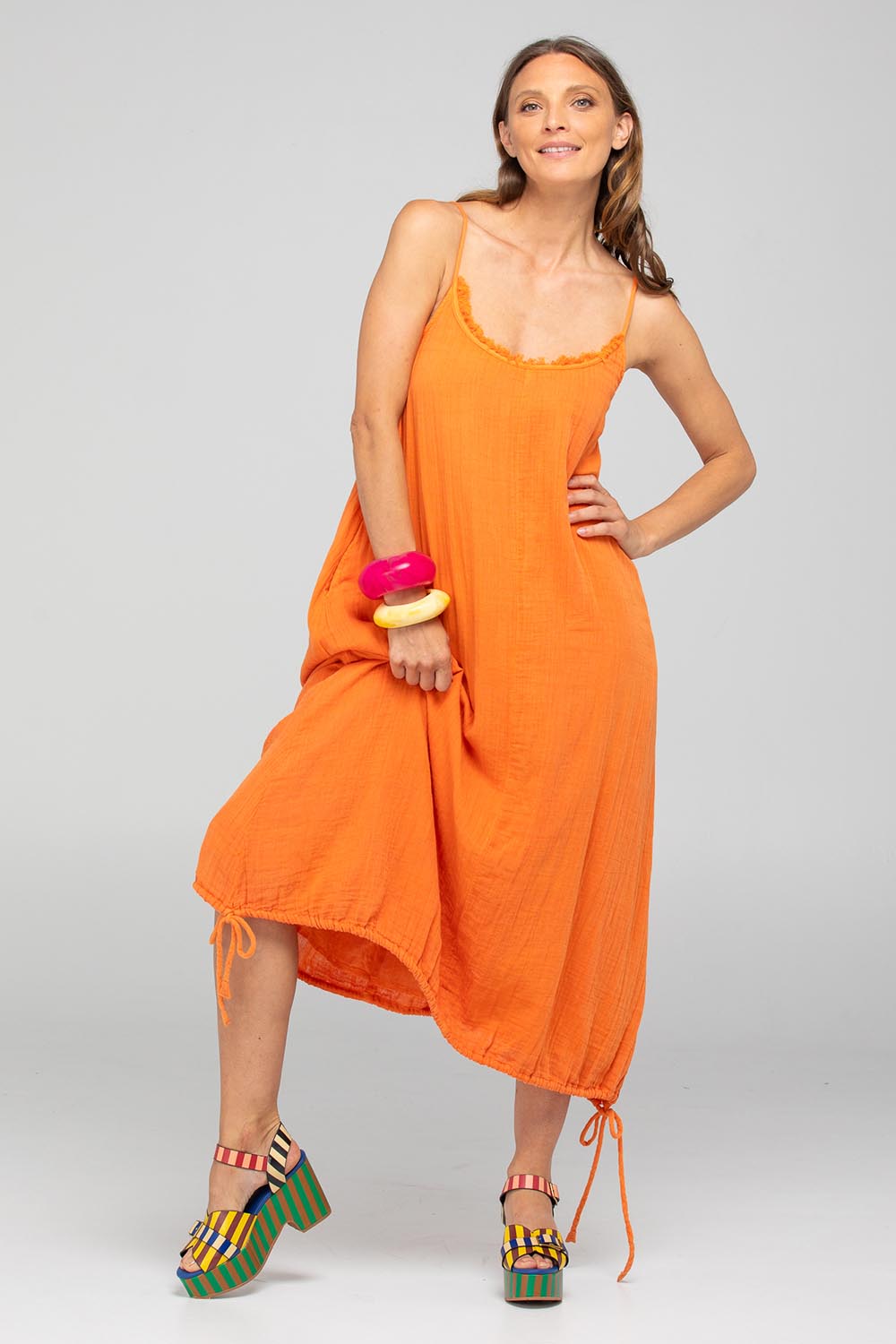 A model wearing the Arena Cotton Dress in colour Tangerine, from the front, showing the whole outfit