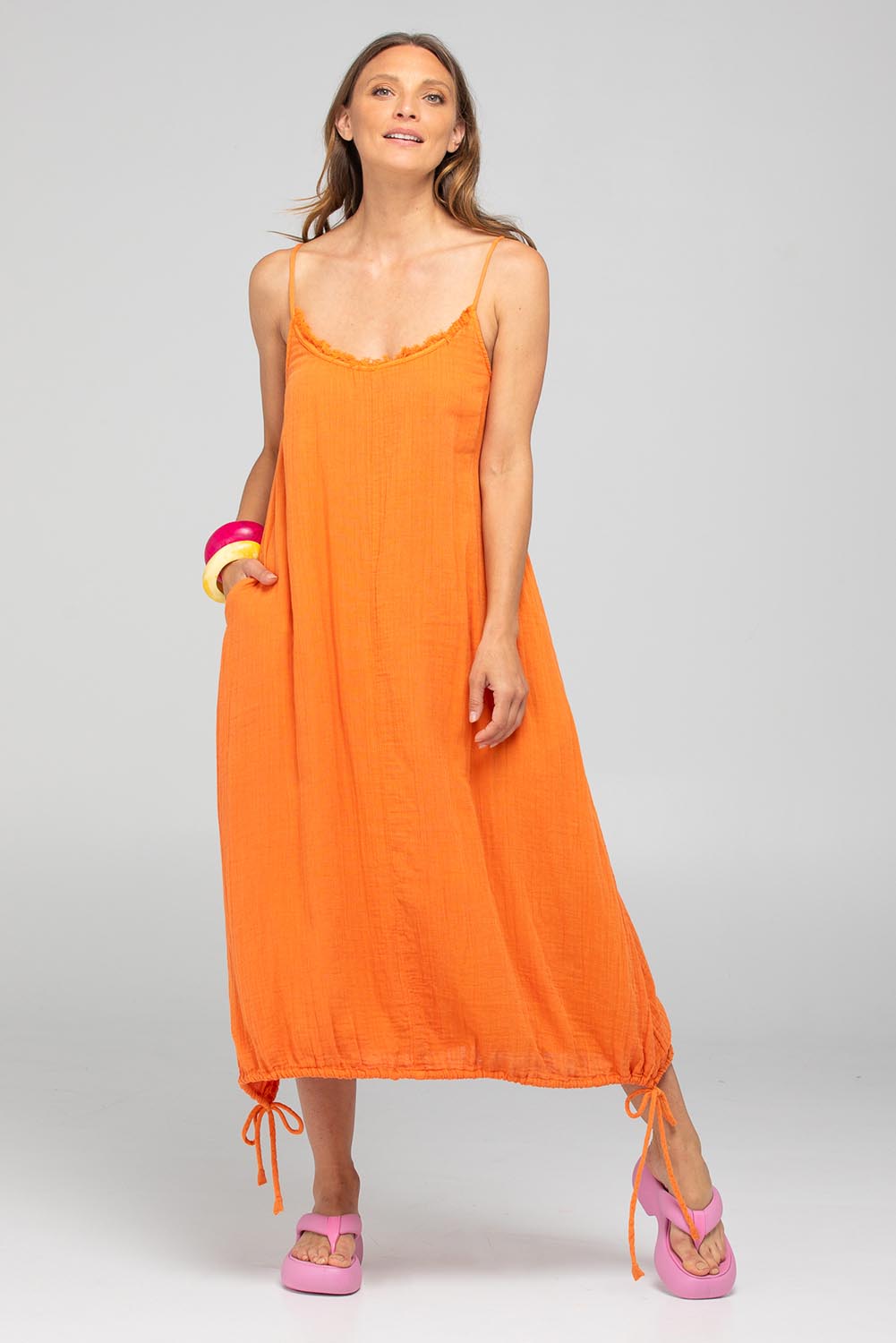 A model wearing the Arena Cotton Dress in colour Tangerine, from the front, showing the whole outfit