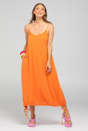 A model wearing the Arena Cotton Dress in colour Tangerine, from the front, showing the whole outfit