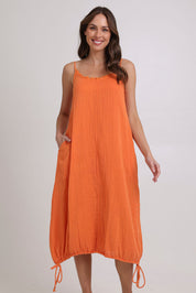 Model Madeline wearing size 10 of the Arena Cotton Dress in colour Tangerine, from the front, showing the whole outfit